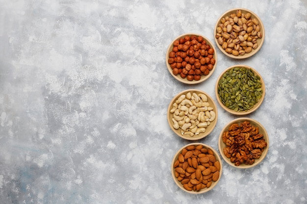 Assortment of nuts in ceramic plates. cashew, hazelnuts, walnuts, pistachio, pecans, pine nuts, peanut, raisins.top view Free Photo