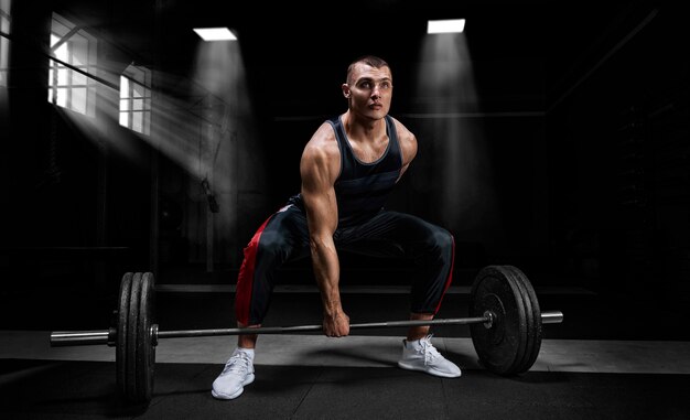 Premium Photo | Athlete is standing on his knee and near the bar and is ...