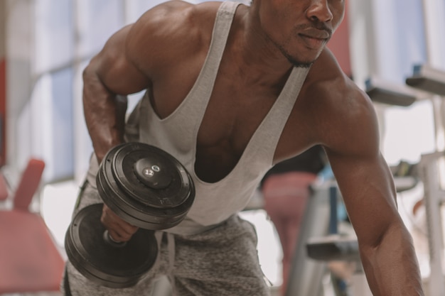 Premium Photo | Athletic african man working out with dumbbells at the gym