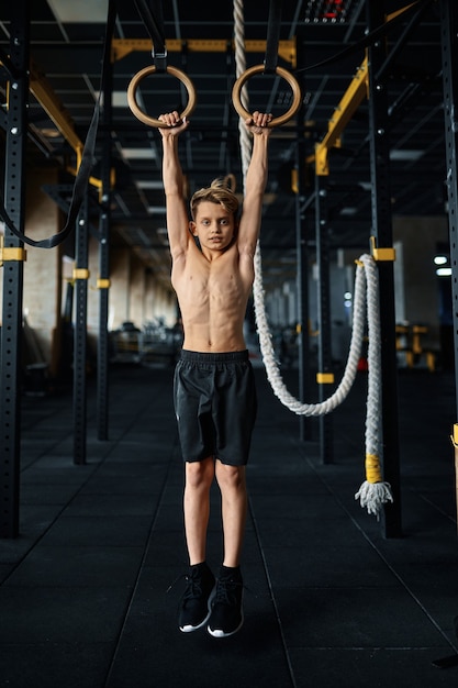 Premium Photo | Athletic boy doing exercise on rings in gym. youngster ...