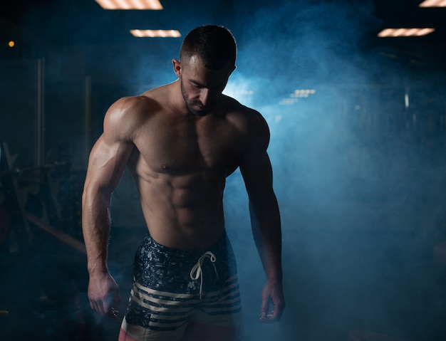 Premium Photo | Athletic man with a muscular body poses in the gym ...