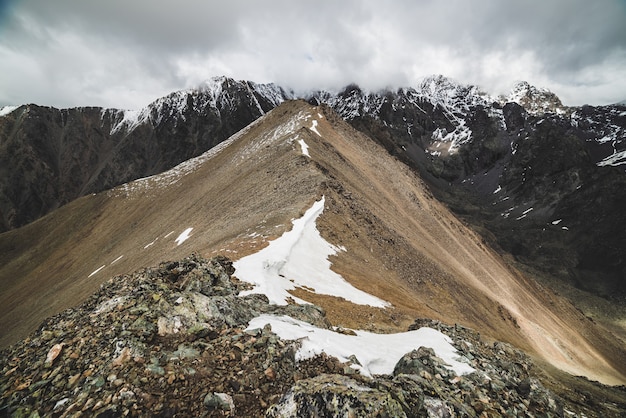 Premium Photo Atmospheric Minimalist Alpine Landscape To Massive Snowy Mountain Range Firn Or Snow On Combe Rocky Hill Cloud Sky Over Big Snowbound Ridge Rock Of Boulder Stream Majestic Scenery On