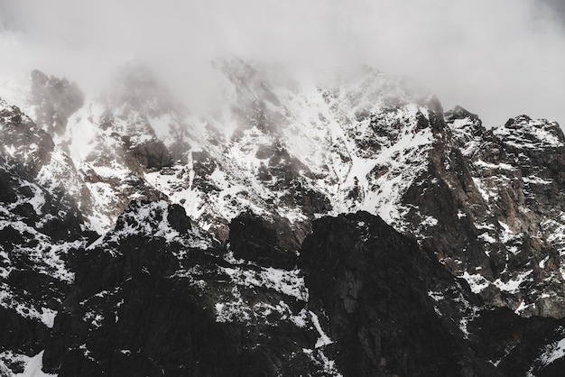 Premium Photo Atmospheric Minimalist Alpine Landscape With Snowy Rocky Mountain Peak Low Clouds Near Snowbound Range Rocks With Snow In Mist Craggy Mountains In Fog Majestic Misty Foggy Scenery On High