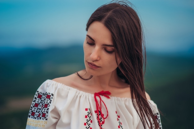 山緑背景をぼかした写真にルーマニアの伝統的な衣装で魅力的な女性 プレミアム写真