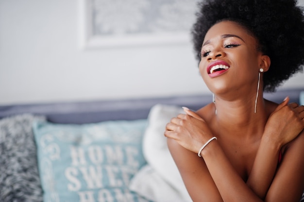 白い部屋で提起されたスカートピンクのトップにアフロの髪を着て魅力的なアフリカ系アメリカ人女性 おしゃれなセクシーブラックモデル プレミアム写真
