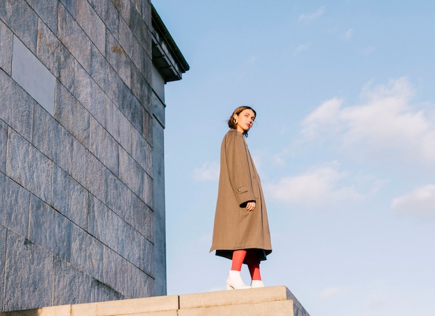 An attractive beautiful young woman standing in front of wall against sky Free Photo