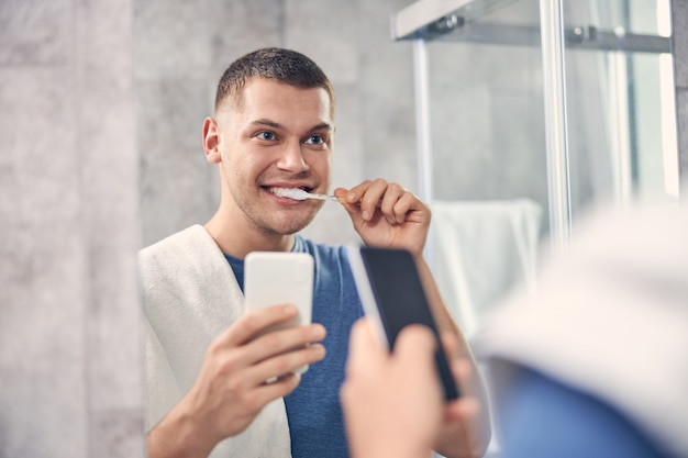 Premium Photo | Attractive brunette male cleaning teeth in from of the ...