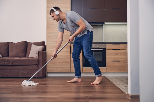 Premium Photo | Attractive brunette man with mopping stick washing ...