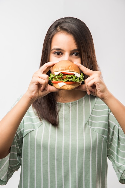 Premium Photo | Attractive indian asian girl eating burger on white or ...