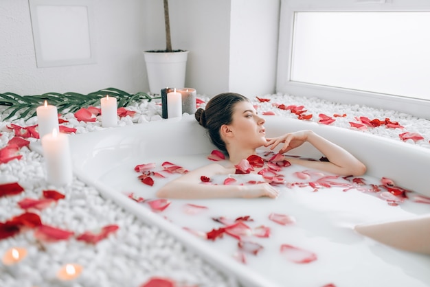 Attractive lady lying in bath with rose petals Premium Photo