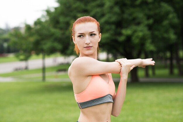 Premium Photo Attractive Redhead Girl Stretching Her Arm And Shoulder In The Park