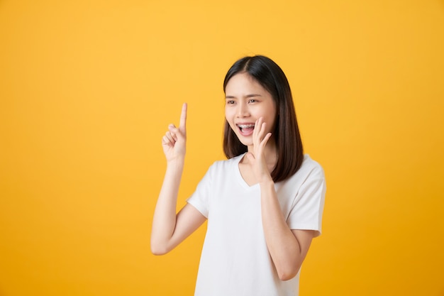 Premium Photo Attractive Young Asian Woman Announcing With Hands To The Mouth And Telling A Secret Isolated On Light Orange Background