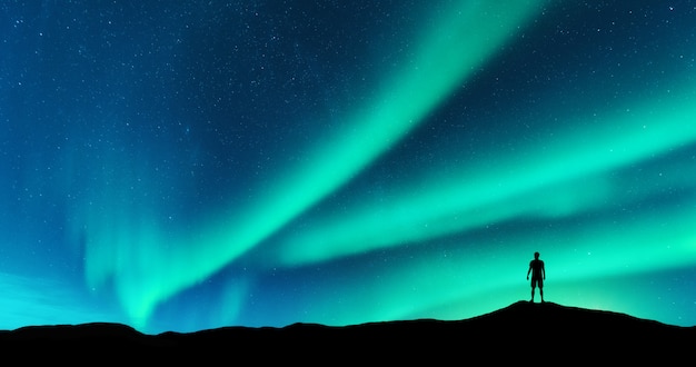 Premium Photo | Aurora and silhouette of alone standing man on the hill ...