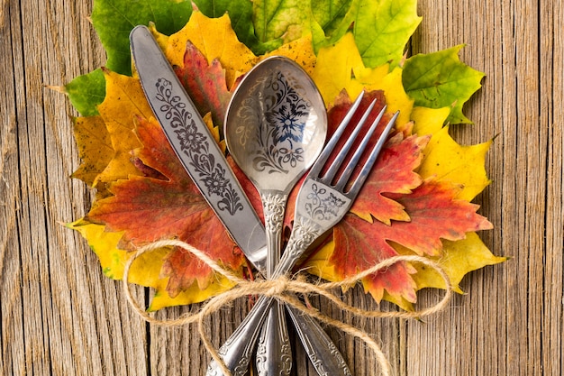 Autumn dinner place setting for thanksgiving holiday with colorful maple leaves on rustic wooden boards Premium Photo