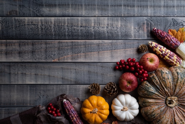 Autumn maple leaves with pumpkin and red berries on wooden background. thanksgiving concep Premium Photo