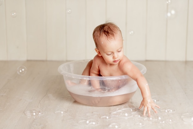 Premium Photo The Baby Bathes Or Washes In A Basin With Foam And Soap