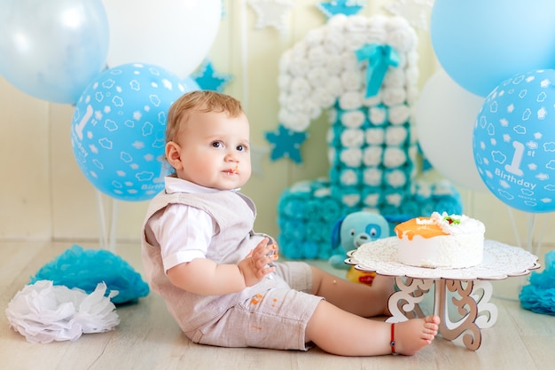 1歳の男の子とケーキと風船 子供の誕生日1歳 赤ちゃんがケーキを食べる プレミアム写真