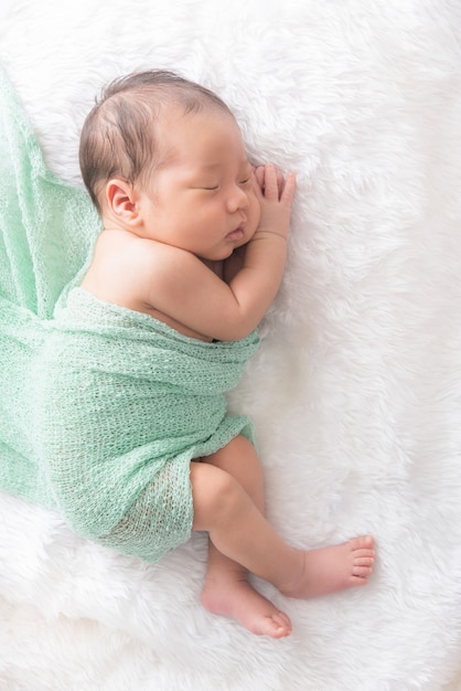 白いラップ布の上で寝る男の赤ちゃん プレミアム写真