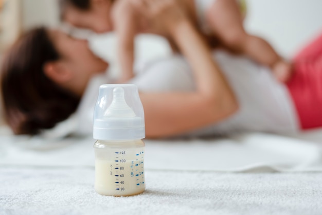 Baby formula with mom and baby in the background Free Photo