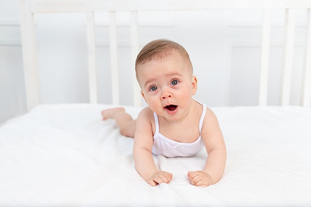生後6ヶ月の赤ちゃんが彼女の胃の保育園でベッドに横になっているとあくび 赤ちゃんの朝 ベビー用品のコンセプト プレミアム写真