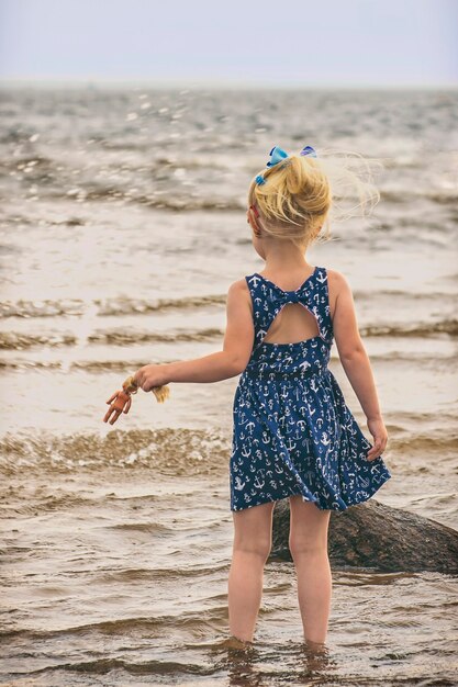 Premium Photo | Baby girl in blue dress on the of the cold baltic sea ...