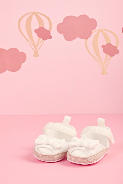 雲と風船とピンクのパステル調の背景の上の女の赤ちゃんかわいいピンクの靴 プレミアム写真