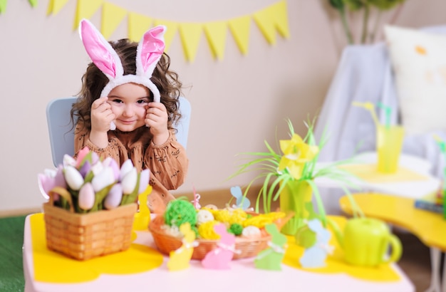 Premium Photo | Baby girl in rabbit ears sitting at table on surface of ...