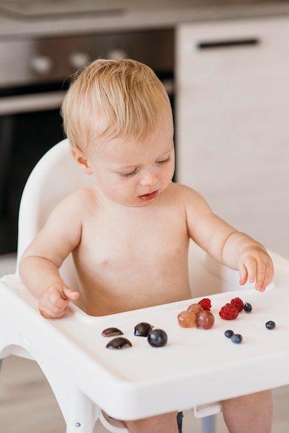 食べる果物を選ぶハイチェアの赤ちゃん 無料の写真