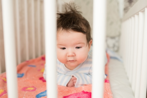 ベビーベッドの赤ちゃん 白い天蓋付きベッドで面白い赤ちゃん 子供部屋のインテリアと子供用寝具 プレミアム写真