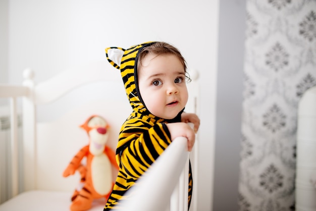 タイガーコスチュームの赤ちゃん 彼女のベビーベッドで楽しんでください プレミアム写真