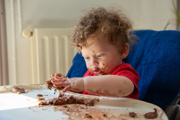 赤ちゃんはチョコレートケーキを食べています プレミアム写真