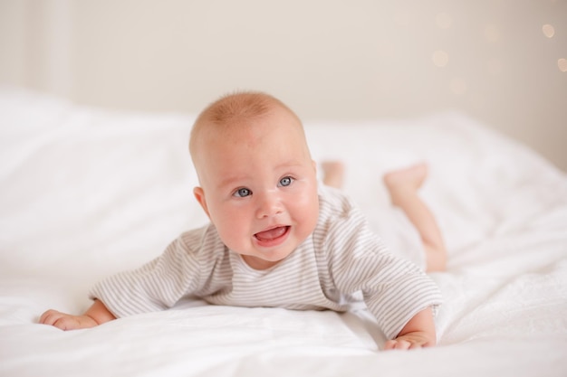 Premium Photo | The baby is lying at home on the bed smiling