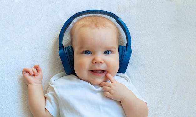 Premium Photo | The baby listens to music in wireless blue earphones ...