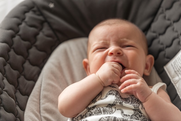 Baby lying and crying with fingers in her mouth teething with first tooth top view healthc