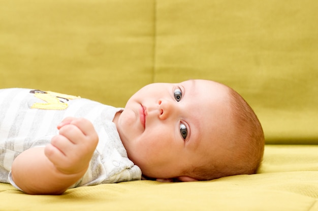 Premium Photo Baby Lying On The Green Couch Serious Look
