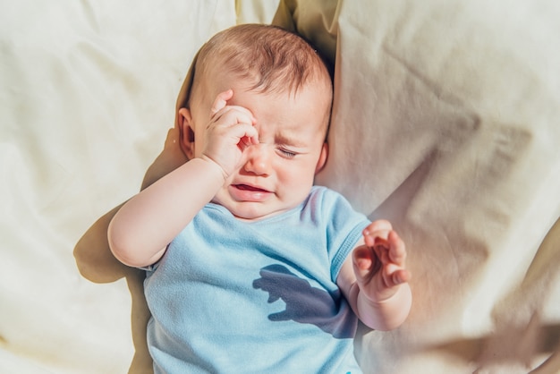 Premium Photo | Baby lying in the sun angry and crying calling his parents.