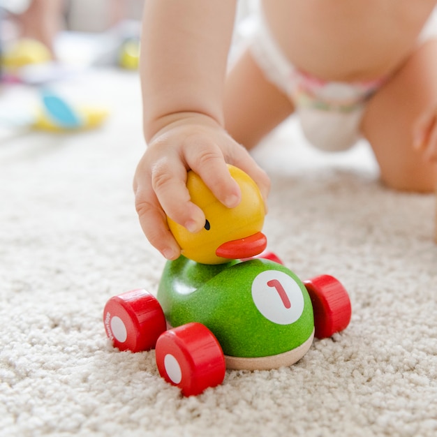 Baby playing with a wooden car Free Photo