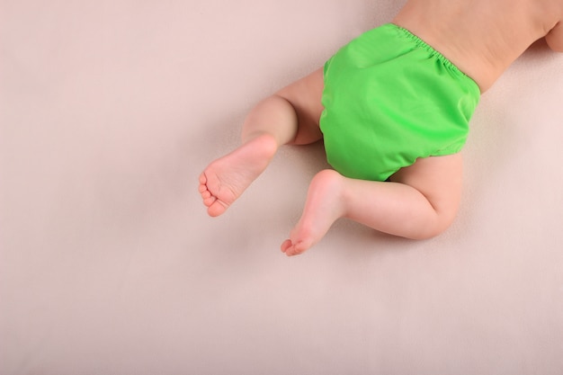 Baby's feet and green reusable diaper.  zero waste baby care concept. Premium Photo