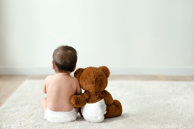 Baby and teddy bear rear view with design space Free Photo