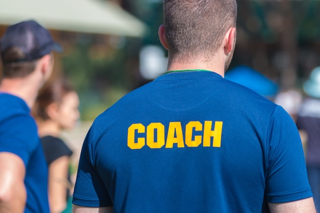 Premium Photo | Back of a coach's blue color shirt with the word coach ...