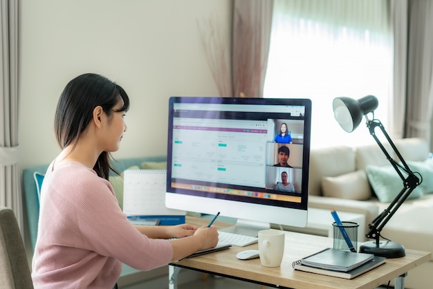 Back view of asian business woman talking to her colleagues about plan in video conference. Premium Photo