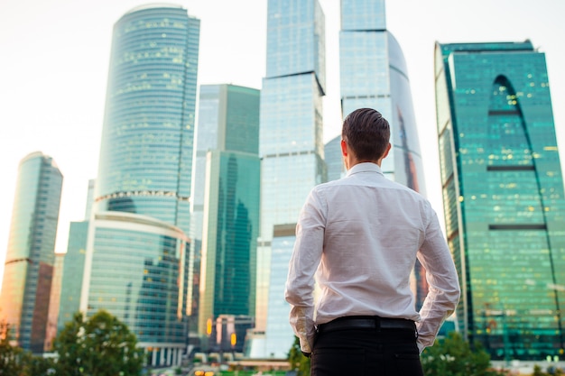 Back view of businessman looking on copy space while standing against glass skyscraper Premium Photo