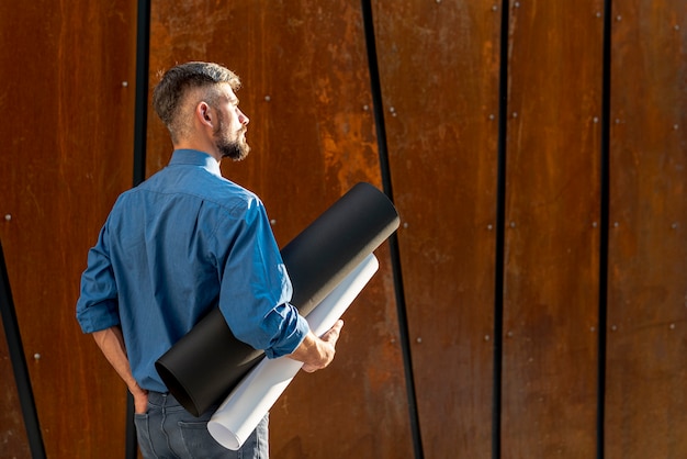 Back view of man with construction plan Free Photo