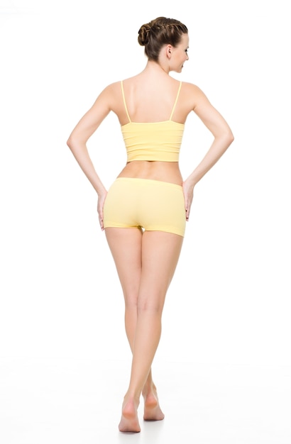 白い壁に分離されたポーズの黄色い下着で美しいスポーティな女性の身体の背面図 無料の写真