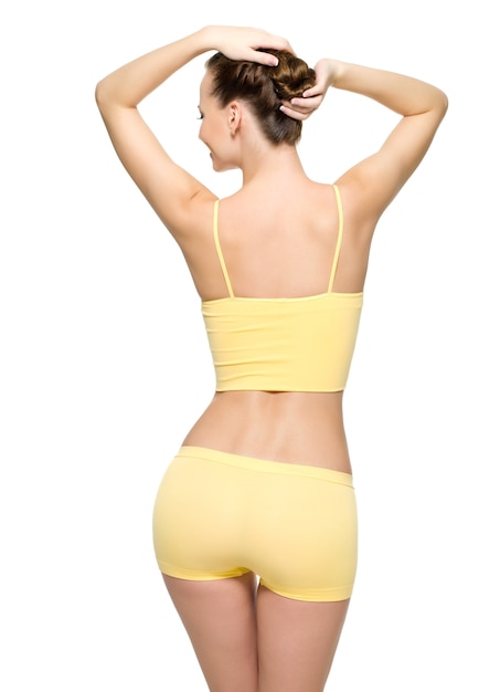 白い壁に分離されたポーズの細い腰で完璧な女性の身体の背面図 無料の写真