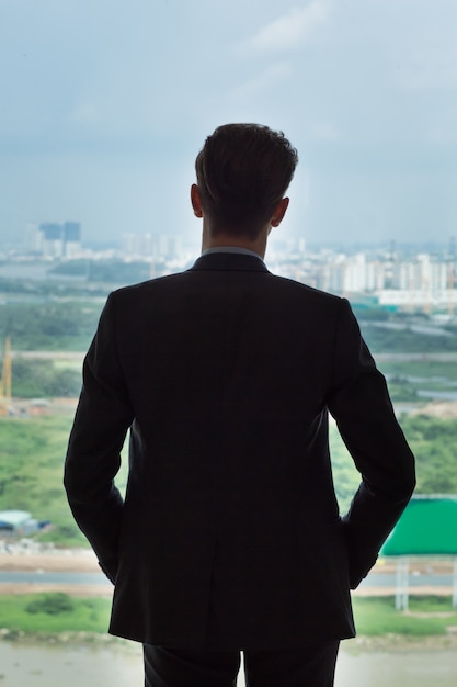 Back View of Businessman Standing by Window Photo Free 