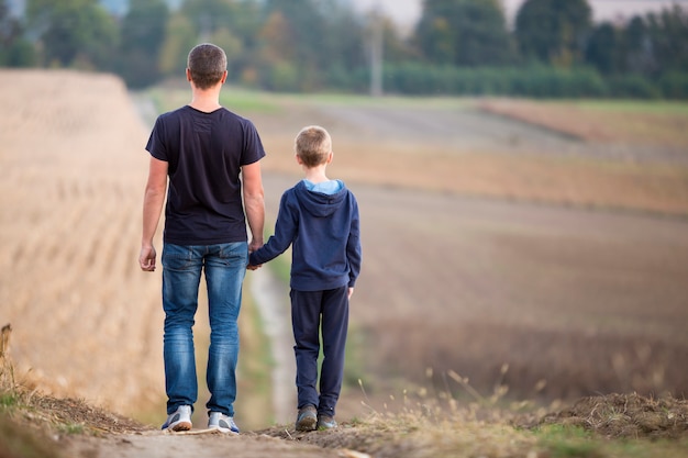 Premium Photo | Back view of young father and son walking together ...