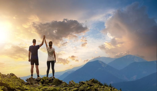 Premium Photo | Back view of young hiker couple standing with raised ...