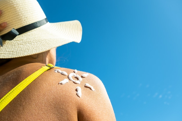 Premium Photo Back View Of Young Woman Tanning At The Beach With Sunscreen Cream In Sun Shape