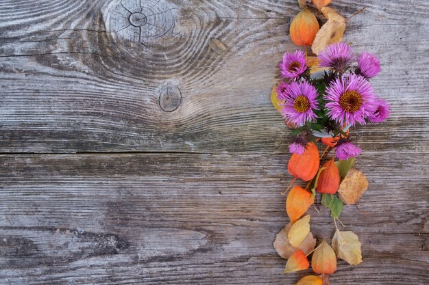 古い木の板の秋の花 菊 サイサリス 黄色の葉の背景 プレミアム写真